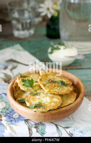 Pancakes with zucchini and sweet corn, served with sour cream, parsley and dill. Vegetarian food. Stock Photo