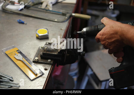 Laborer using an electric drill while metalworking Stock Photo