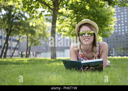 Pretty Young Woman Lying on the Grass with Book Stock Photo