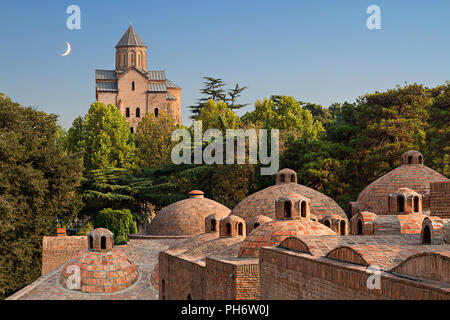 Domes of sulphur baths and Metekhi Church with crescent moon in the sky in Tbilisi, Georgia Stock Photo