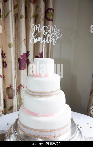 wedding cake with cake topper that says mr and mrs smith on it at their wedding day Stock Photo