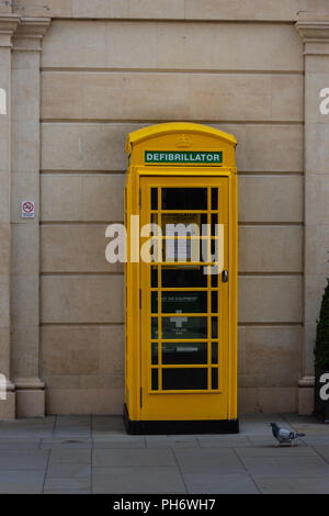 Traditional telephone box painted yellow and used for a defibrillator to be stored and accessed by the public in an emergency Stock Photo