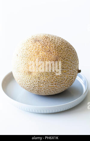 Single whole Charentais melon or Cantaloupe on a plate Stock Photo