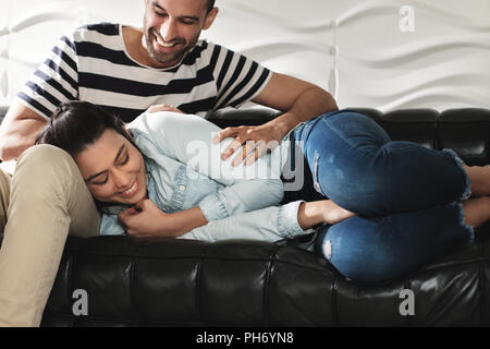 Happy Latino Couple Having Fun And Laughing On Sofa Stock Photo
