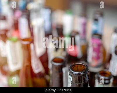 Close-up various types of empty bottled beer on wooden counter bar. Stock Photo