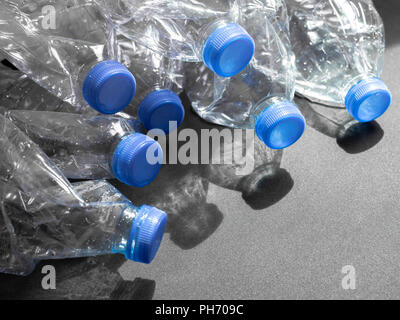 Empty crushed recycle clear plastic drink water bottles on black background with light and shadow with copy space. Global warming concept. Stock Photo