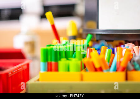 Close up image of pots of coloured pens and crayons in a school art classroom Stock Photo