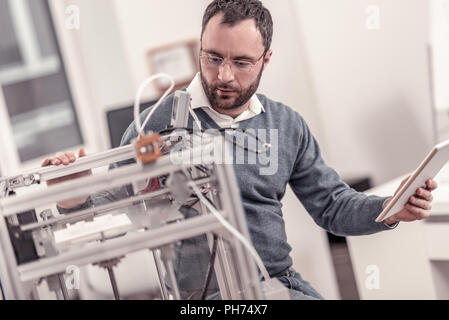 Bearded adult man adjusting 3D printers components Stock Photo