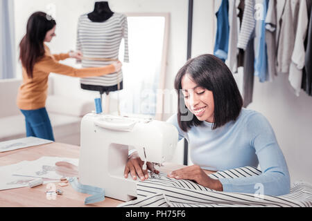 Cheerful seamstress working in personal studio Stock Photo