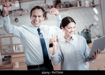 Excited entrepreneurs putting hands up and celebrating their success Stock Photo