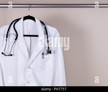 Medical white consultation coat with stethoscope and pens on hanger Stock Photo