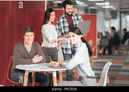 Nice young students sitting at table Stock Photo