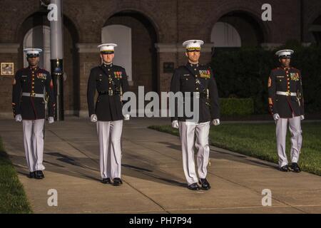 Marines with the Marine Barracks Washington D.C. parade marching staff march to their positions on Center Walk during a Friday Evening Parade at the Barracks, June 29, 2018. The guest of honor for the ceremony was the Under Secretary of the Navy, Thomas B. Modly, and the hosting official was the Assistant Commandant of the Marine Corps, Gen. Glenn M. Walters. Stock Photo