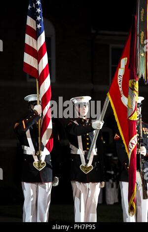 Marines with the U.S. Marine Corps Color Guard present the National Ensign while the National Anthem is played during a Friday Evening Parade at Marine Barracks Washington D.C., June 29, 2018. The guest of honor for the ceremony was the Under Secretary of the Navy, Thomas B. Modly, and the hosting official was the Assistant Commandant of the Marine Corps, Gen. Glenn M. Walters. Stock Photo