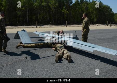 Soldiers assigned to the Horsemen platoon of Delta Company, 91st Brigade Engineer Battalion, 1st Armored Brigade Combat Team, 1st Cavalry Division inspect a RQ-7B Shadow unmanned aircraft system post flight at the Horsemen Flight Landing Strip in Zagan, Poland, June 29, 2018. The platoon conducted the first tactical UAS flight in Poland. They’re currently deployed in support of Atlantic Resolve in Europe. Stock Photo