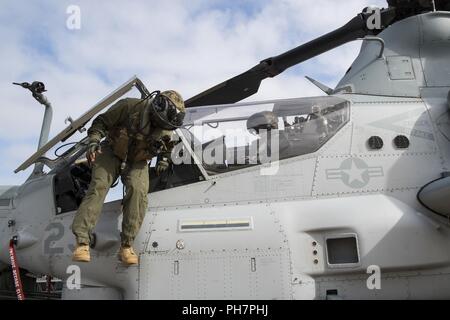 United States (June 28, 2018) Marine Capt. Julian Tucker, from Philadelphia, debarks an AH-1Z Viper, assigned to Marine Light Attack Helicopter Squadron (HMLA) 367, on the flight deck of the amphibious assault ship USS Bonhomme Richard (LHD 6) during the squadron embarkation. Bonhomme Richard is currently in its homeport of San Diego, preparing for an upcoming scheduled deployment. Stock Photo