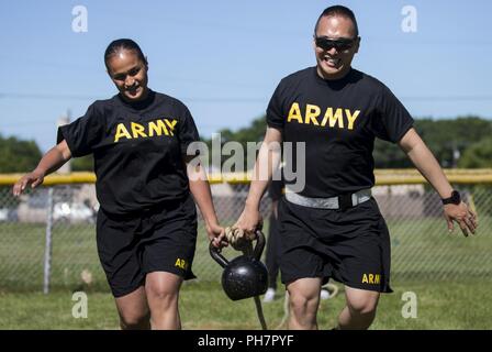 Sgt. Nathlalie Figueroa, of the 812th Military Police Company, and 1st Lt. Jinho Park, of the 333rd MP Brigade, use teamwork to carry a kettle bell through an obstacle course during a Fit Camp hosted at Joint Base McGuire-Dix-Lakehurst, New Jersey, June 15, 2018. U.S. Army Reserve Soldiers from the 333rd MP Brigade had the opportunity to attend the Fit Camp, which lasted June 2-16, 2018, hosted by the 336th MP Battalion. The battalion provided the Soldiers with training, coaching and mentorship for the duration of the Fit Camp with the goal of improving their physical fitness and educating the Stock Photo