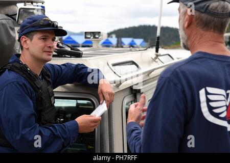 Coast Guard Petty Officer 1st Class Kyle Vaders, a boatswain's mate from the Maritime Safety and Security Team in Seattle chats with locals while docked at Silver Beach Marina on Lake Coeur d'Alene in Idaho, June 30, 2018. Two boat crews worked alongside Kootenai County Sheriff deputies to ensure recreational boating safety during the 4th of July holiday week. Stock Photo