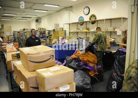 Naples, Italy. (June 29, 2018) – Sailors and Marines of Fleet Logistic Center (FLC) Sigonella, site Naples, unload and organize a truck load of mail from Rome at NSA Naples June 29, 2018. FLC Sigonella receives roughly 333,000 shipments and sends out about 49,000 a year for four individual sites. Stock Photo