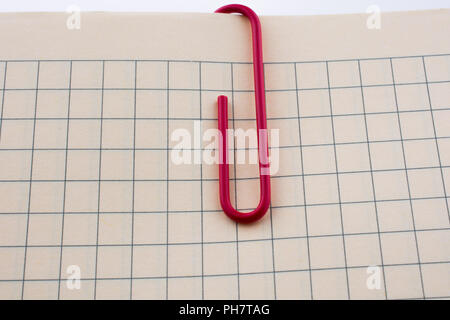 Colored paper clip on a checked notebook  page Stock Photo