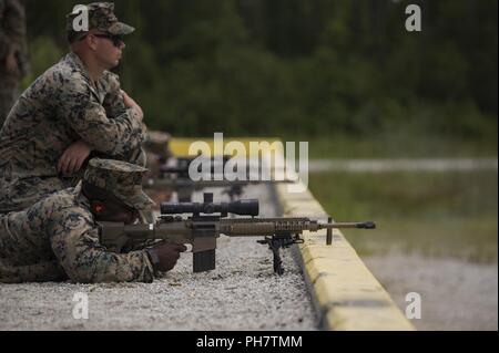 U.S. Marine Corps Cpl. Dakota Morrison with 2nd Law Enforcement Battalion, II Marine Expeditionary Force Information Group supervises 1st Lt. Ade Mubarak as he fires an M110 Semi-Automatic Sniper System during a live-fire range, testing a new autonomous robotic system at Camp Lejeune, N.C., June 27, 2018. The Marines used the targets to further develop their marksmanship skills, anticipate natural movement and increase combat effectiveness. Stock Photo