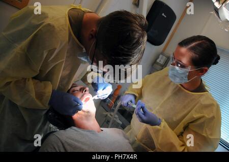Capt. Paul Kearney (left), a general dentist assigned to 7404th Medical Support Unit, and Pvt. 1st Class Lauren Schildt (right), prepare to extract an Illinois resident’s tooth during Innovative Readiness Training (IRT) exercise Southeast Illinois Wellness.   Services provided by military personnel are done through the Department of Defense’s Innovative Readiness Training, a civil-military program that builds mutually beneficial partnerships between U.S. communities and the DoD. The missions selected meet training & readiness requirements for Army Reserve service members while integrating them Stock Photo