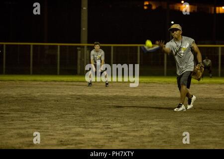 CAMP FOSTER, OKINAWA, Japan- Staff Sgt. Mario Minton pitches the ball  June 28 during the round-robin portion of the 2018 Pacific-Wide Firecracker Softball Tournament aboard Camp Foster, Okinawa, Japan. Twenty-five teams battled through the night in this year’s multi-day tournament to be named the 2018 champions. Minton is a distribution management specialist with Headquarters and Support Battalion, Marine Corps Installations Pacific-Marine Corps Base Camp Butler, Japan. Stock Photo