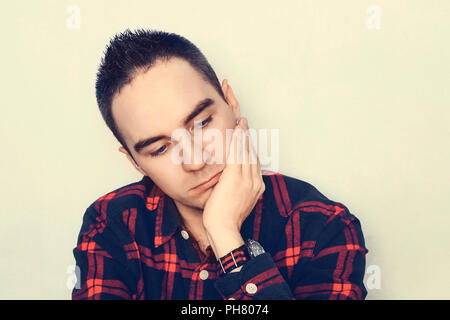 young man thinking. The modern hipster guy holds hand over his head in a thoughtful pose. A sad expression on her face. Depression. Stock Photo
