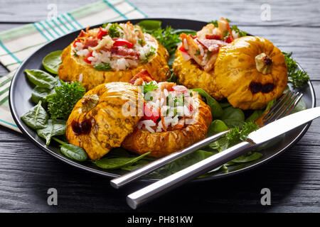 close-up of  baked Pattypan squash stuffed with rice, fried chicken meat, crispy fried bacon, bell pepper and served with green fresh spinach leaves a