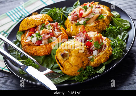 close-up of  baked Pattypan squash stuffed with rice, fried chicken meat, crispy fried bacon, red bell pepper and served with spinach leaves and parsl