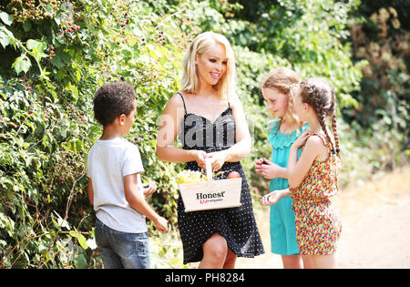 TV personality Katie Piper surprises a group of children, including 8 year old Ryan Koissi (left), 10 year old Saoirse Addison (centre) and 8 year old Erin Addison (right)with their first ever visit to a farm. The trip comes after it was revealed that a quarter (23%) of UK children have never been to a farm, whilst a fifth (20%) don’t know that apples grow on trees, according to new research by organic juice brand HONEST® Kids. In response, Katie has teamed up with the brand to launch its Pick Your Own Summer campaign, which aims to get kids away from screens and outside fruit picking this sum Stock Photo