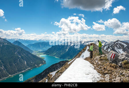 Two hikers on the summit of Seekarspitz, view over the lake Achensee, Tyrol, Austria Stock Photo