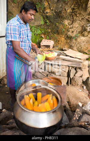 Vertical portrait of a man selling corn-on-the-cob from the roadside in Sri Lanka. Stock Photo