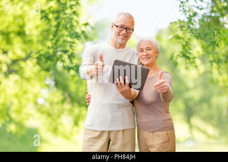 senior couple with tablet pc showing thumbs up Stock Photo