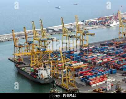 Barcelona industrial cargo port aerial view from Montjuic hill. Yellow cargo cranes and multicolored shipping containers in the Port of Barcelona. Stock Photo