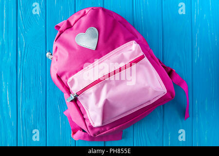 top view of pink backpack on blue wooden background Stock Photo