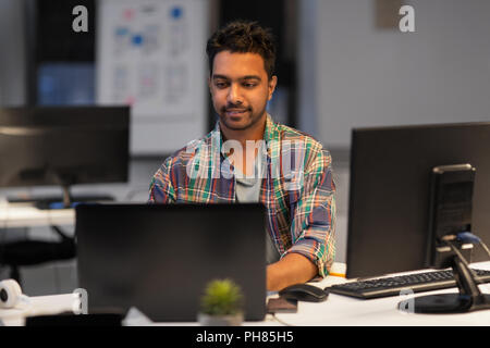 creative man with laptop working at night office Stock Photo