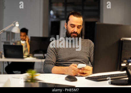 creative man with smartphone at night office Stock Photo