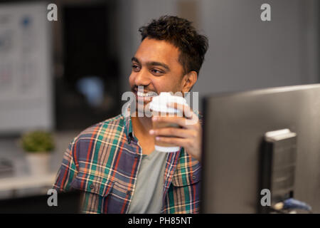 happy creative man drinking coffee at night office Stock Photo