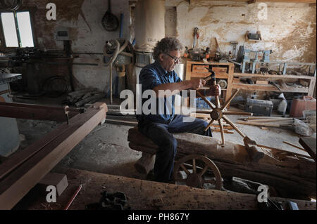 A Menorcan woodworker, or arader, makes a simple wooden wheel in his workshop in Menorca, Spain. Stock Photo