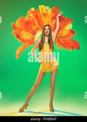 young beautiful dancer with carnival feather and fringe posing on studio background Stock Photo