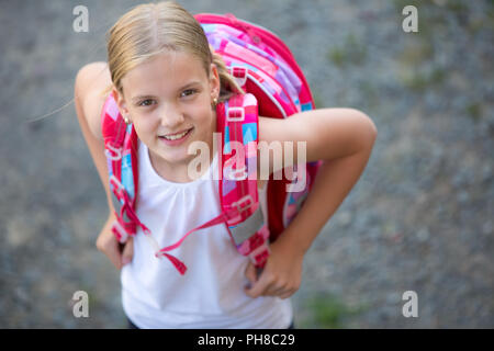 Cute little girl going home from school, looking well before crossing the street Stock Photo