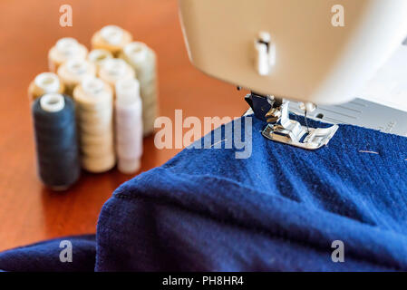Dressmaker or seamstress works using sewing machine. Reels, scissors, tape measure and a sewing machine. Workplace Stock Photo