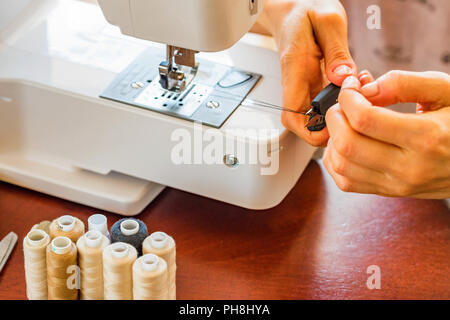 Dressmaker or seamstress works using sewing machine. Reels, scissors, tape measure and a sewing machine. Workplace Stock Photo