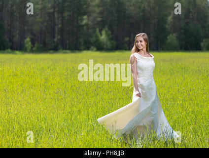 Cute girl holding white dress in green field Stock Photo