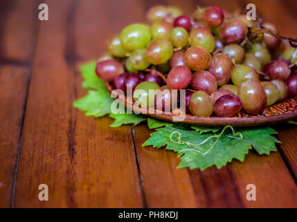 Grapes on a clay plate on a wooden tables .Still life with pink muscat grapes. Stock Photo