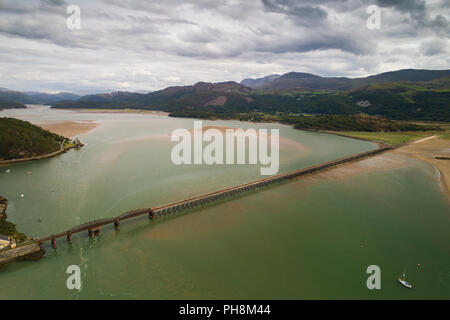 An aerial drone view of the railway viaduct bridge over the Mawddach estuary at Barmouth (Y Bermo / Abermaw in welsh) - a small welsh town and seaside resort , Gwynedd, Snowdonia National Park, North Wales UK (made by a CCA licenced and insured drone operator) Stock Photo