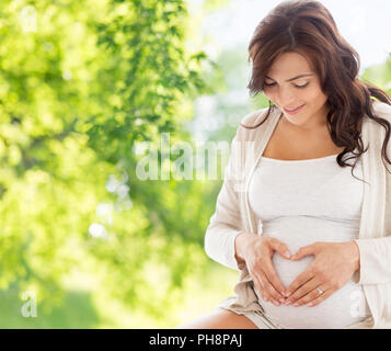 happy pregnant woman making heart gesture Stock Photo