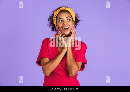 Portrait of an excited young african woman in headband standing over violet background Stock Photo