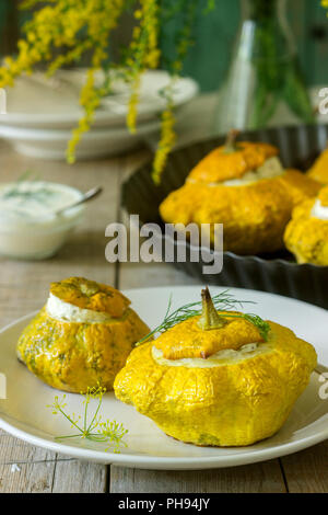 Pattypan squash or pumpkins stuffed with ricotta with basil and dill and served with sour cream sauce. Vegetarian food. Stock Photo